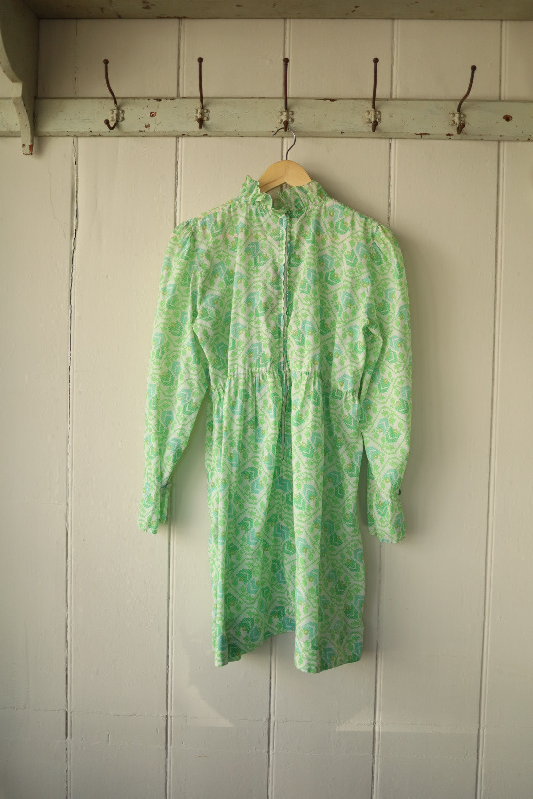 Back view of the green and white pie crust smock dress showing the high neckline and button fastening down the back, with soft gathers creating a flowing silhouette.