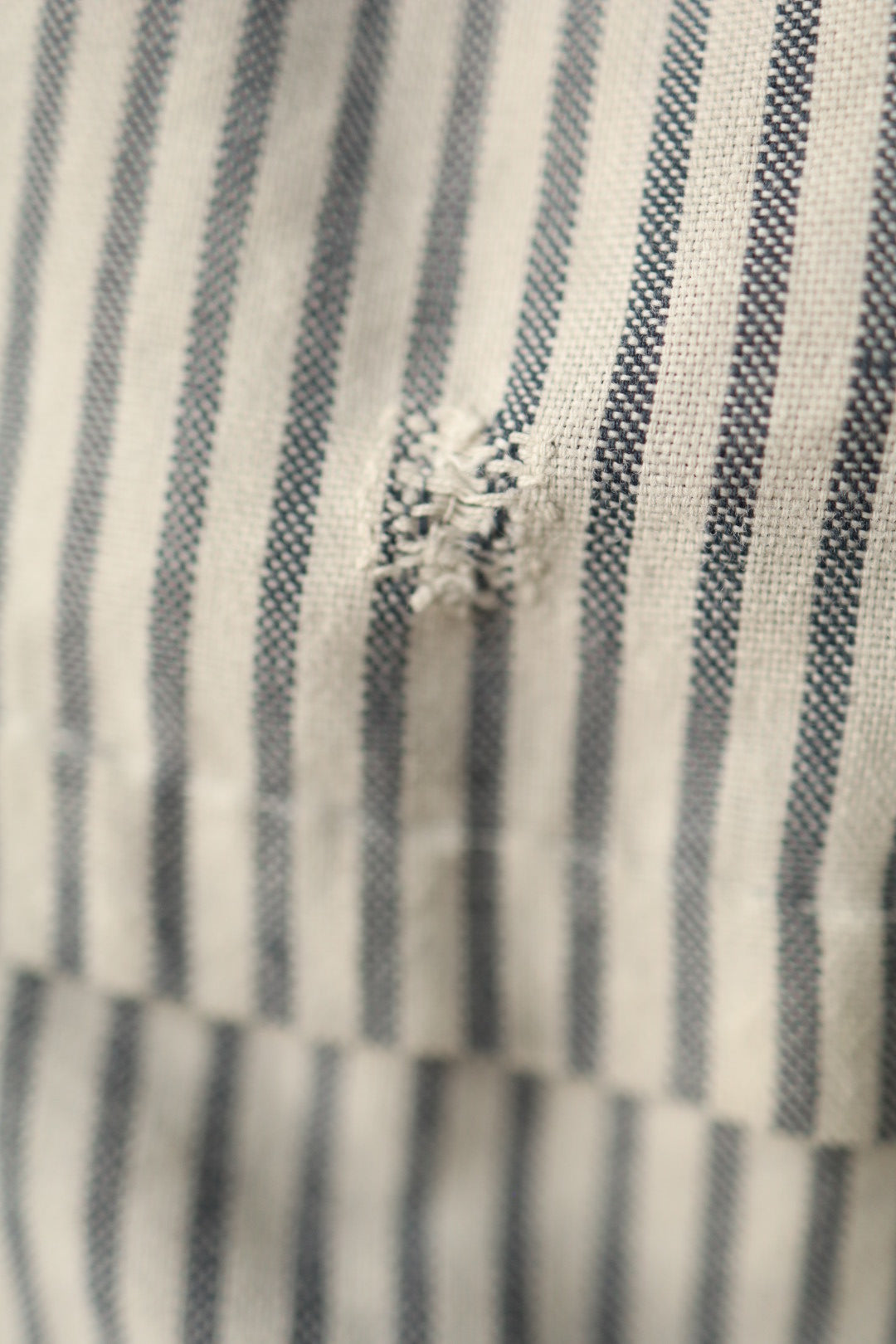 Close-up of repaired area on striped fabric showing visible vintage mending.