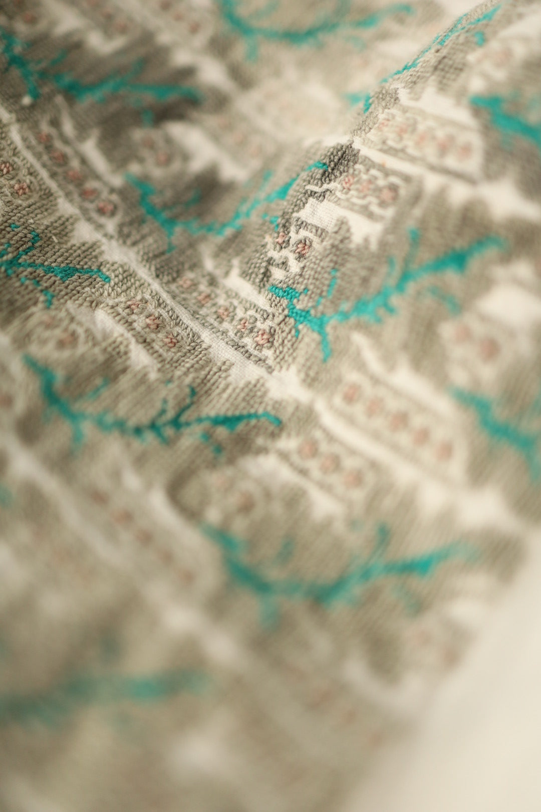 Embroidered sleeve detail with pink, green, and beige cross-stitching