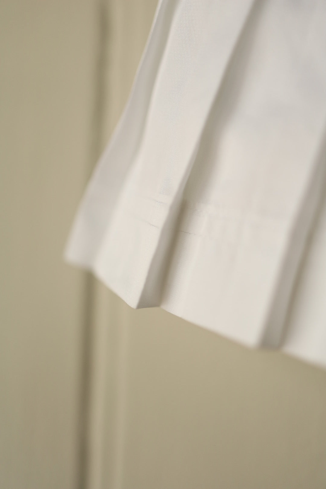 Detailed close-up showing the pleated hem and crisp cotton texture of the white tennis skirt.