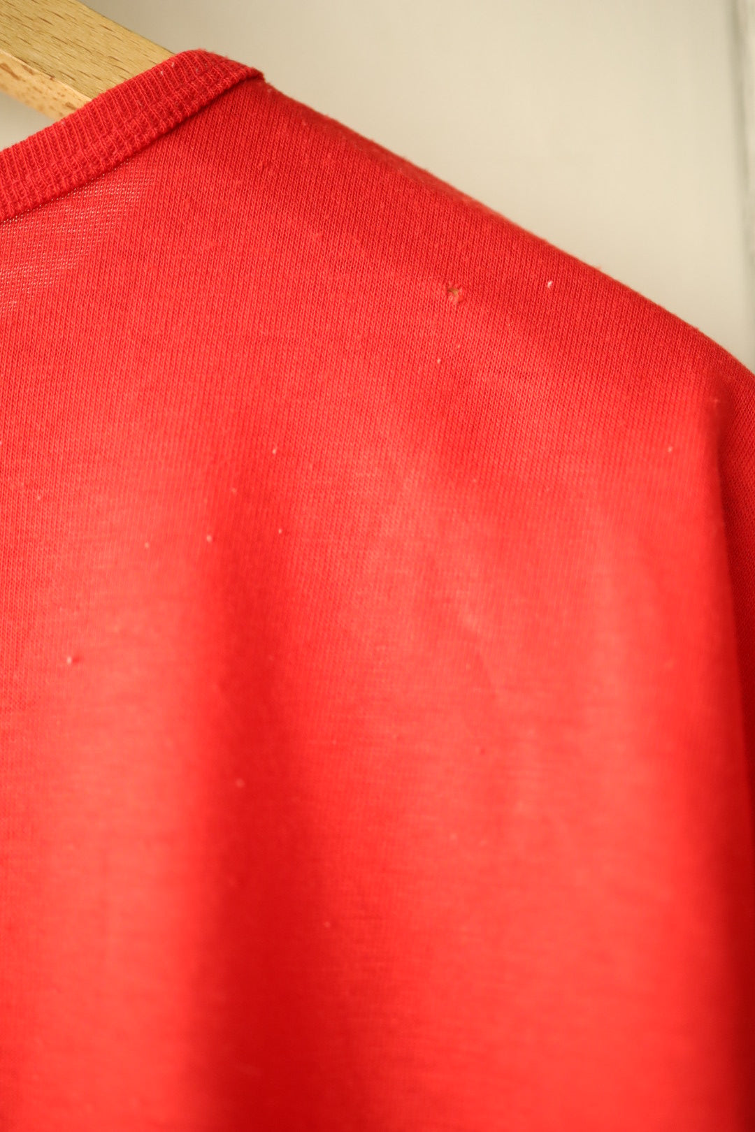 Close-up of small hole on back shoulder area of red tee
