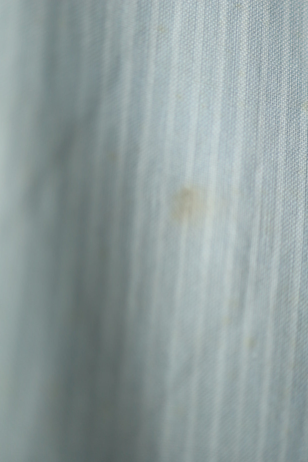 Close-up of subtle fabric wear and faint stain near the lower front section of the shirt.