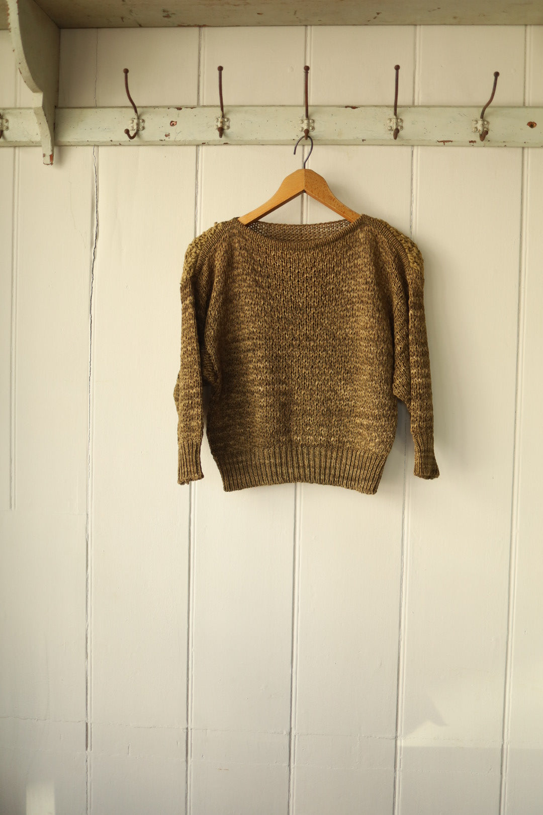 Angled view of the shoulder and upper sleeve, highlighting the contrast between the flat and textured knit areas and the knotted suede tassels.