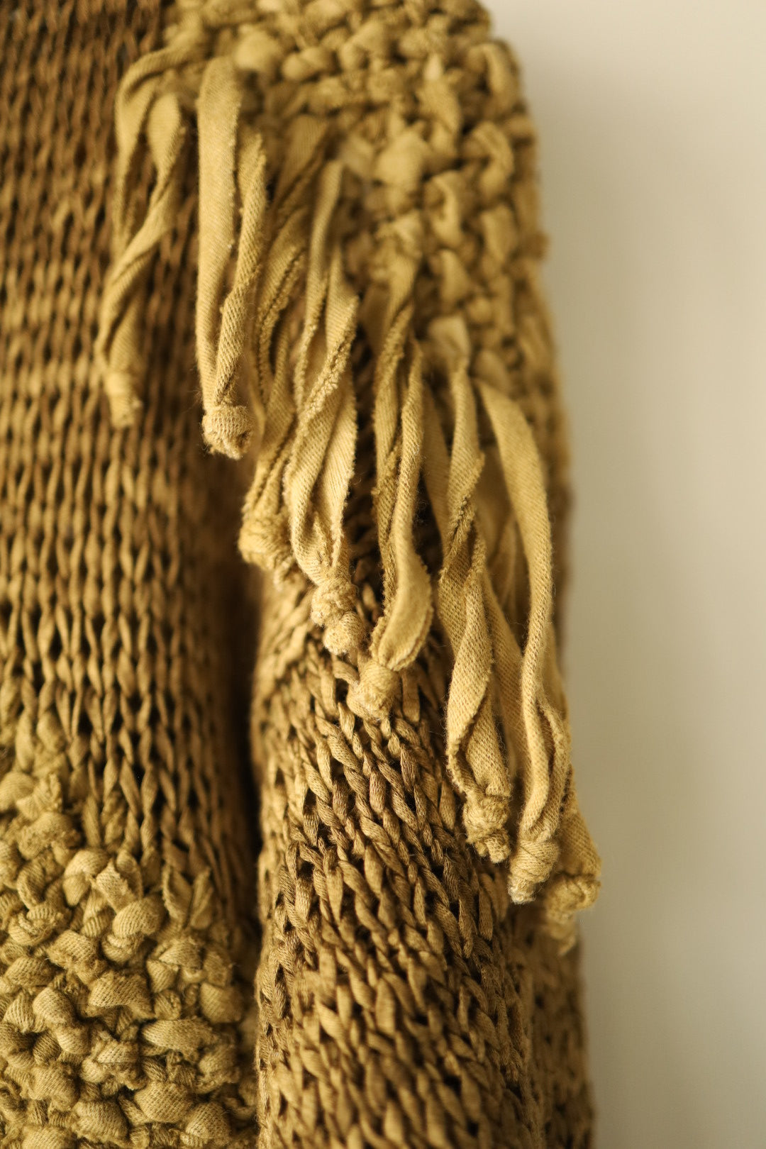 Full back view of a hand-knitted jumper in warm brown tones, featuring a large central diamond-shaped suede intarsia design and shoulder fringe details.