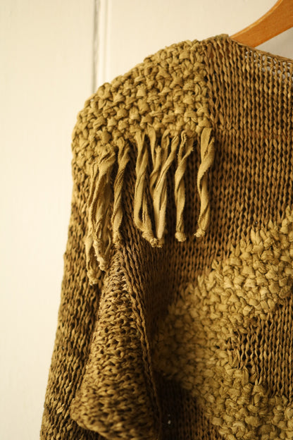 Close-up of the shoulder detailing showing twisted suede fringe emerging from a textured knit section.