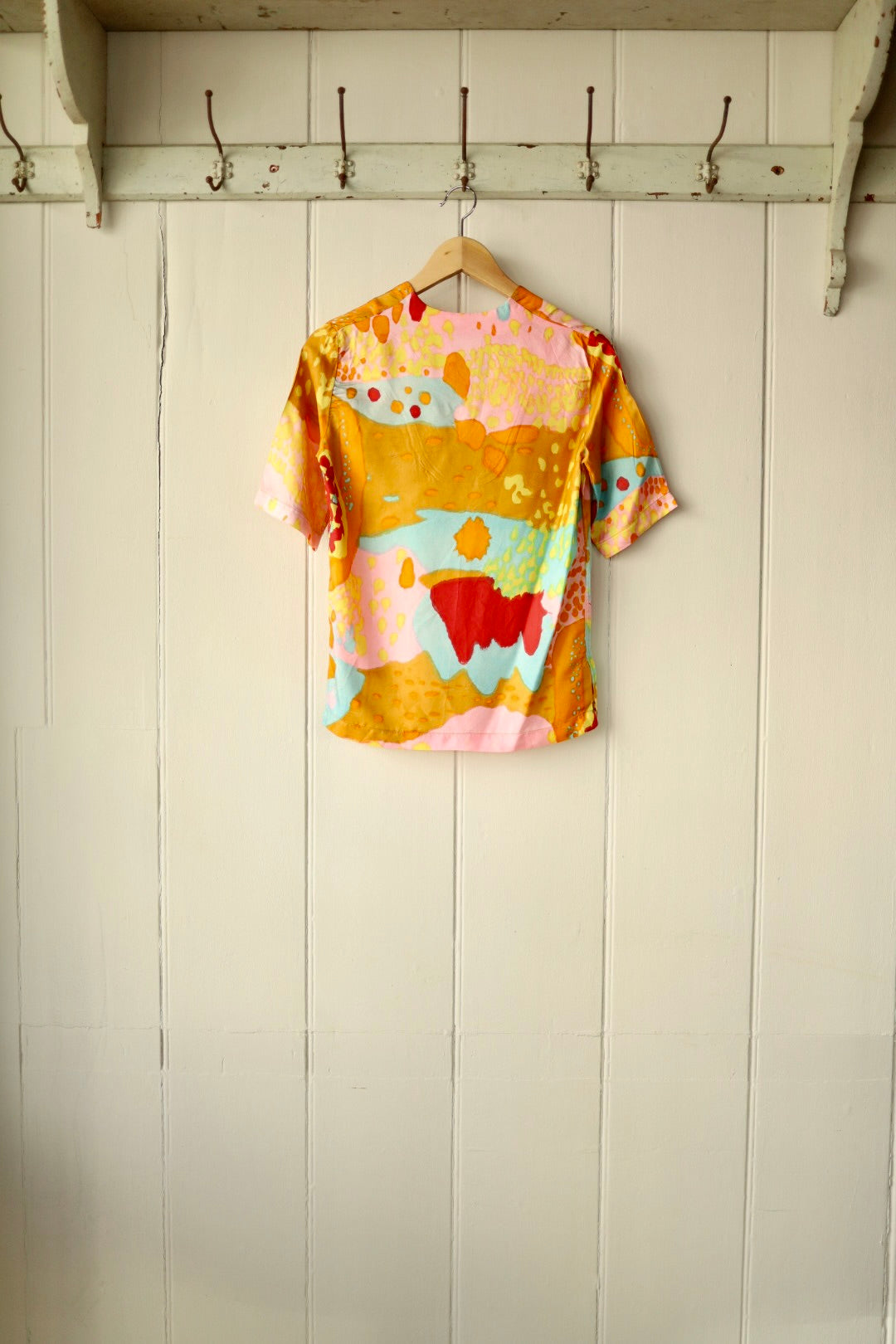 Back view of the same abstract print top, showing the vibrant painterly design and short-sleeve cut.