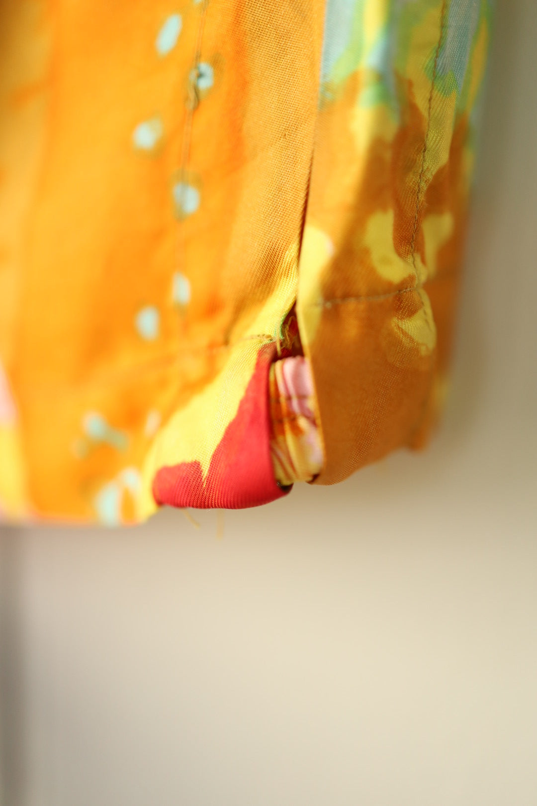 Detail of a repaired hem split on the abstract top, with visible hand-stitching.