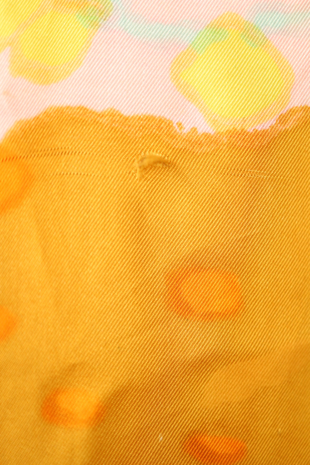Fabric detail of the back showing a faint thread pull in the yellow-orange section of the abstract pattern.