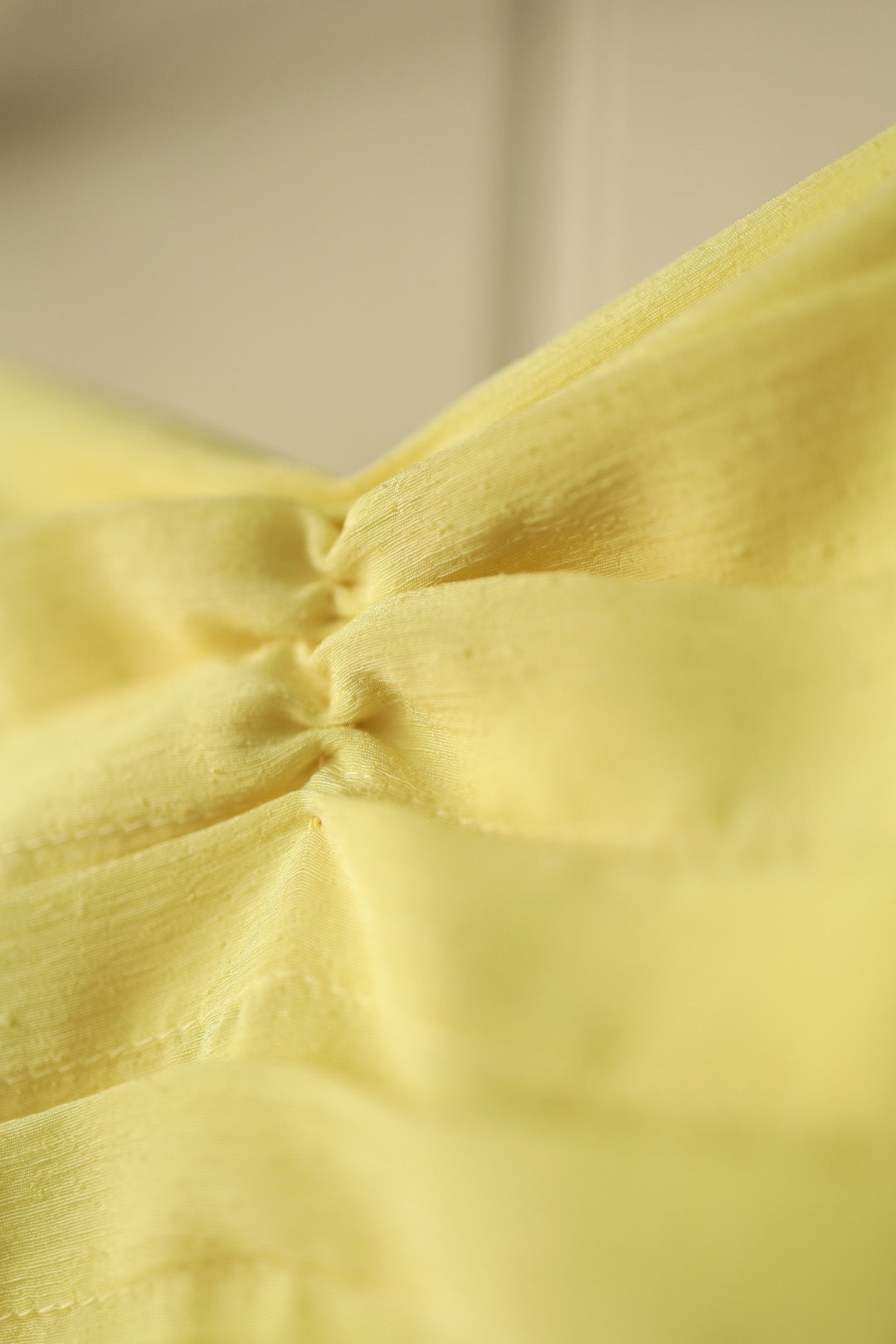Macro shot of the central ruched detailing on the bust of the dress, highlighting the elegant draping and subtle texture.