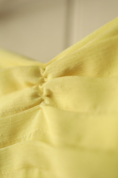 Macro shot of the central ruched detailing on the bust of the dress, highlighting the elegant draping and subtle texture.