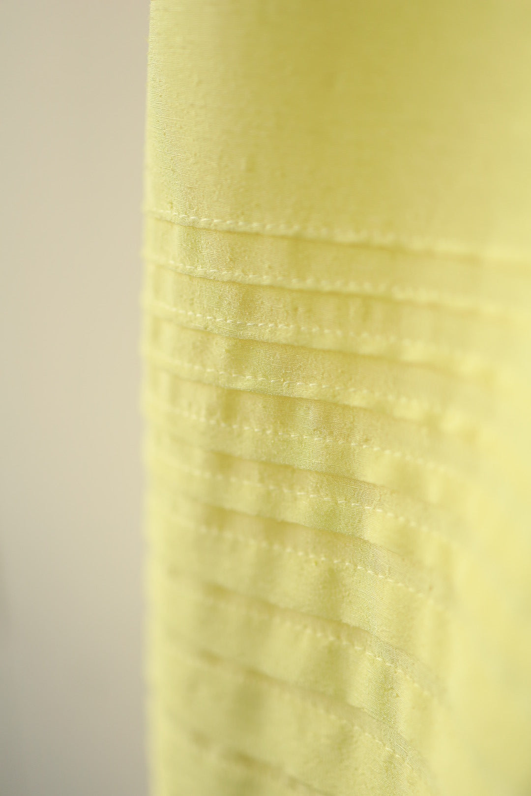 Close-up of the pintuck stitching near the hemline, showing the careful craftsmanship and subtle sheen of the fabric.