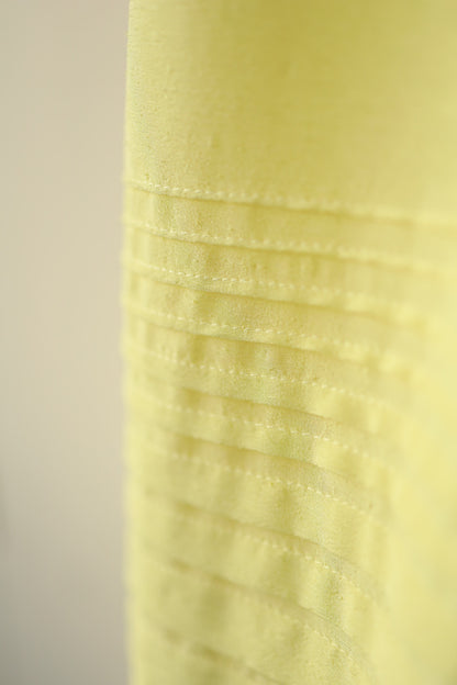 Close-up of the pintuck stitching near the hemline, showing the careful craftsmanship and subtle sheen of the fabric.