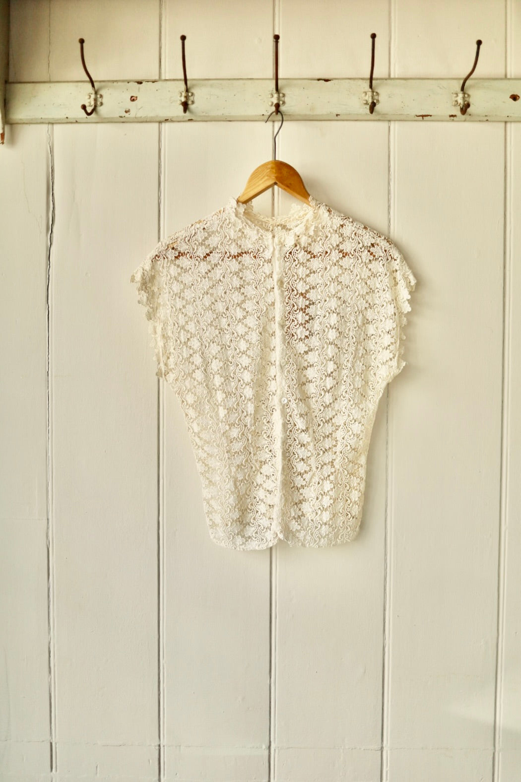 Rear of the Simon Ellis lace blouse showing button fastening and consistent floral lace detailing, with subtle shaping through the waist.