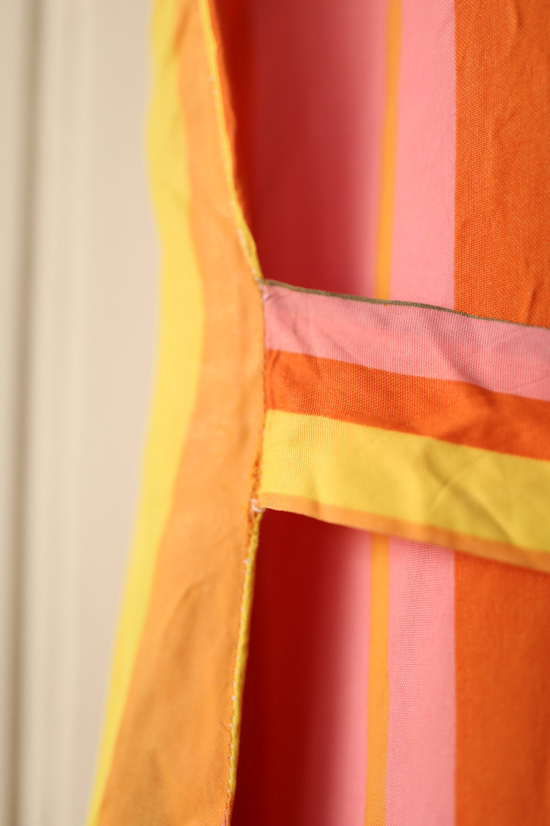 Close-up of the gathered striped pocket on the side of the dress, with colours in pink, yellow, and orange tones.