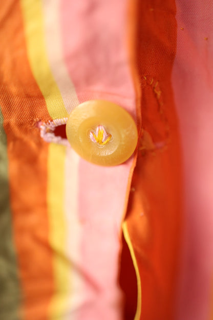 Detailed view of one of the yellow buttons with contrast pink and yellow thread stitching through the buttonhole.