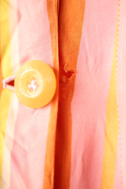 Close-up showing wear around the buttonhole area, with fraying of the fabric in orange and pink stripes.