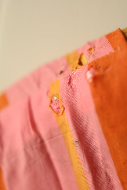 Detailed image of the inner neckline showing multiple small holes and thinning fabric in pink and orange stripes.
