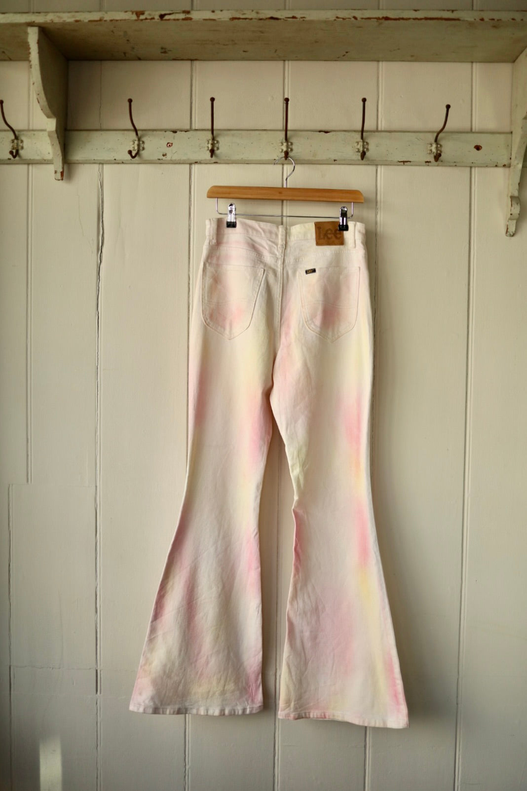 Rear view of the same Lee flares, with soft blush-toned fading on the pockets and legs, highlighting the label detail and flare silhouette.