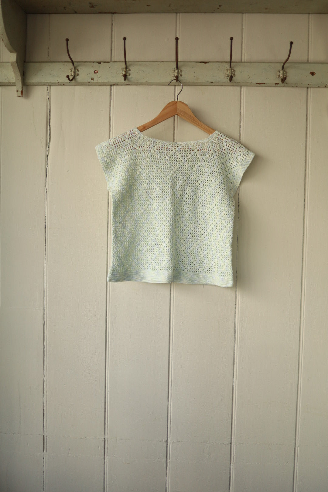 Rear of the same pale blue hand-crocheted cropped top, showing the simple, seamless finish and consistent open stitch detailing.