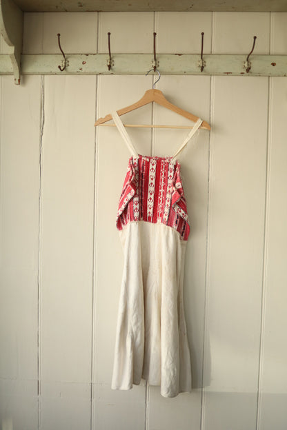 The rear of the dress showing the same woven bust panel and wide cream straps, with visible wear to the fabric.