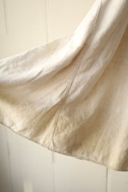 A closer look at the lower portion of the cream skirt, showing signs of age and slight creasing.