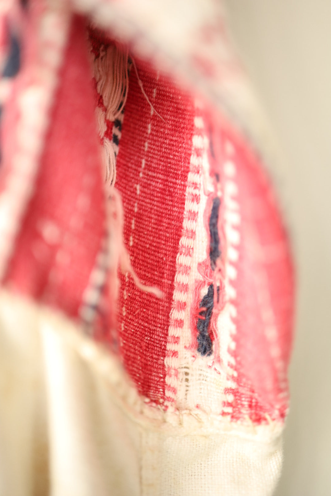 Detailed texture shot of the red and cream handwoven bust panel, showing frayed threads and raw edges.