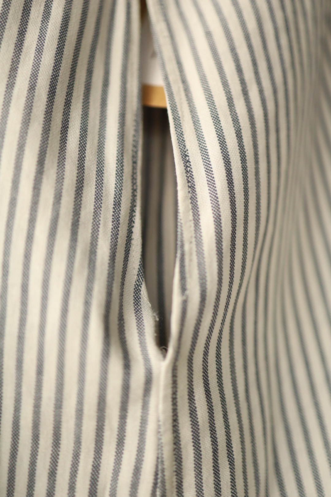 Close-up of back placket where fabric separates at fastening, highlighting hand-stitched detail.