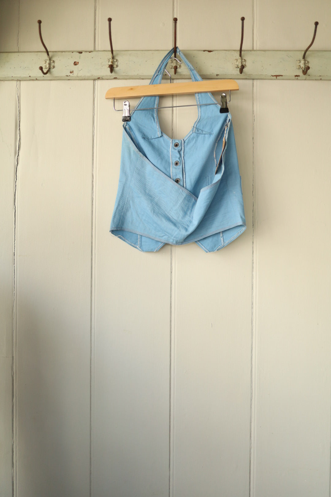 Back view of the same halterneck top showing its open-back design and side detail with front buttons partially unfastened.