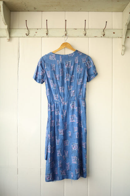 Back view of the same vintage dress showing zipper fastening and fitted waist, displayed on hanger.