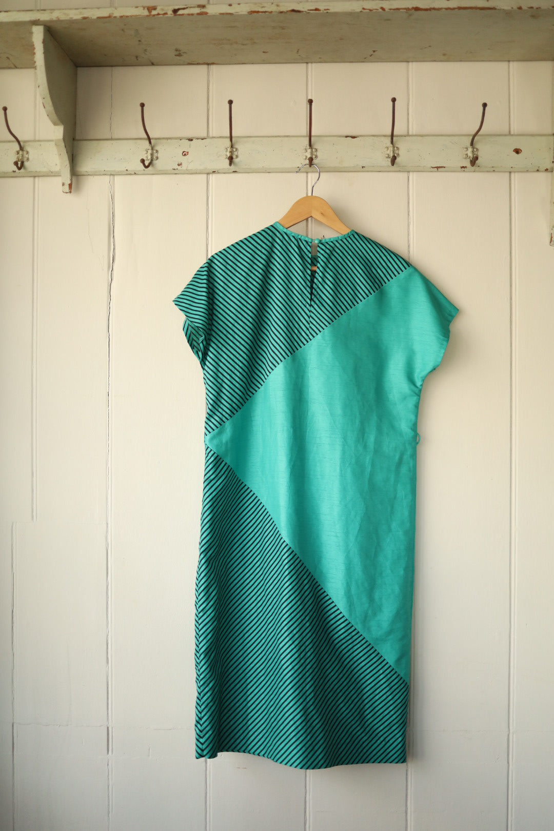 The same dress shown from the reverse, highlighting the continued geometric panel design and button fastening at the nape.