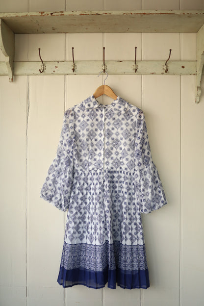 Rear view of the same 70s cheesecloth dress, highlighting the full sleeve detail and zip-back closure, with the patterned fabric gathered at the waist for a voluminous skirt effect.