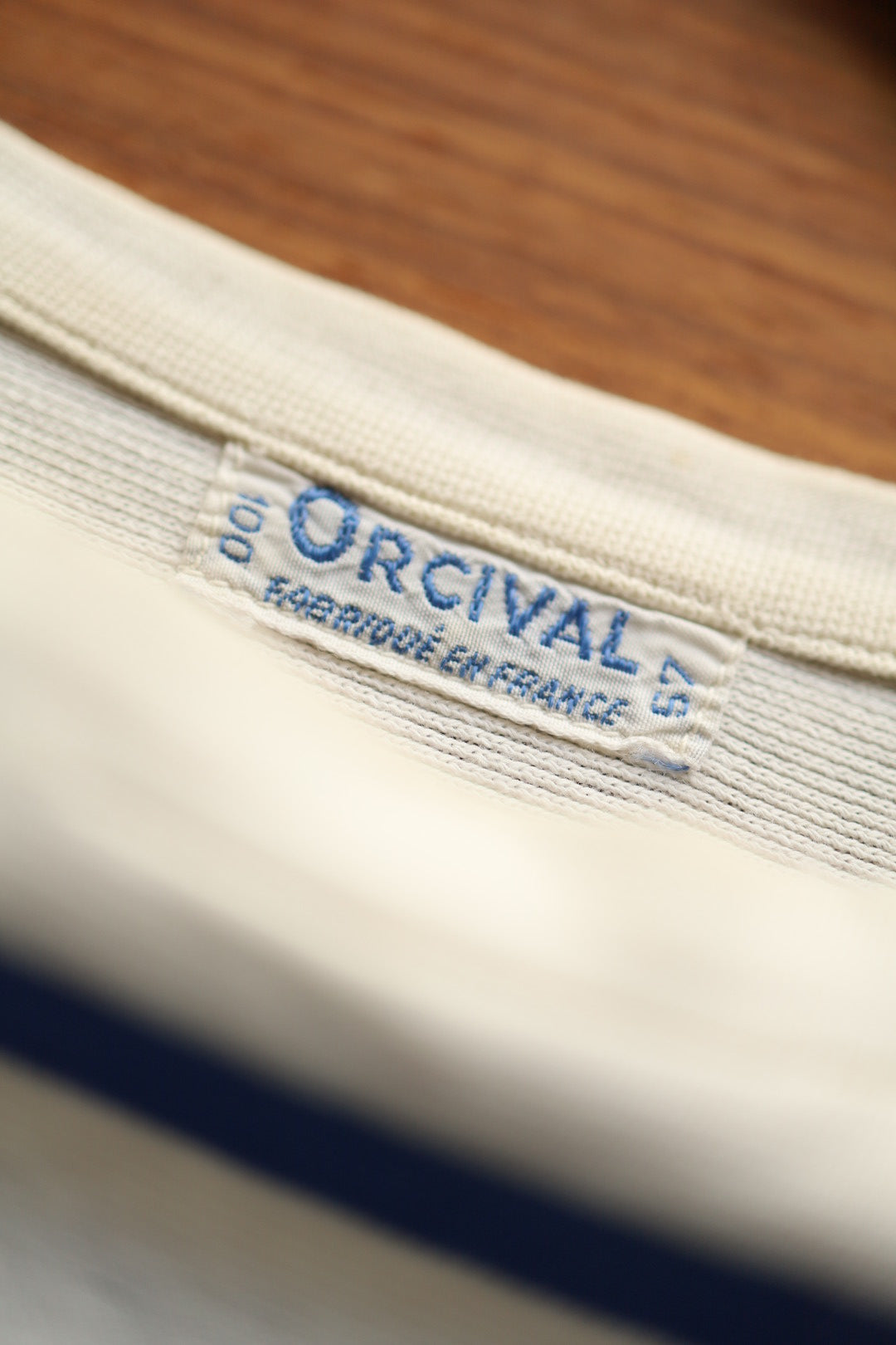 Close-up of the Orcival label stitched into the neckline of a cream and blue Breton dress, showing the brand name and 'Fabriqué en France' text.