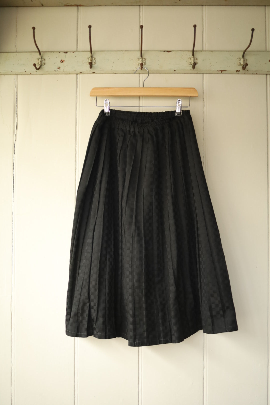 Full front view of handmade black chequerboard midi skirt hanging on wooden hanger