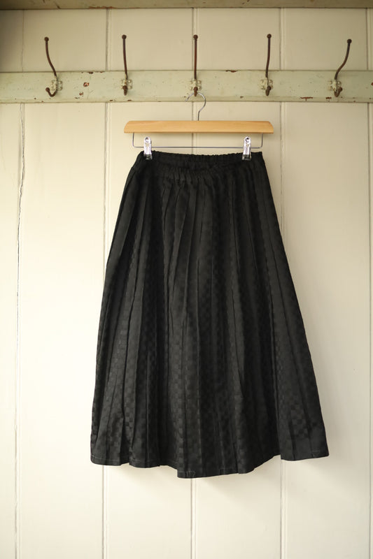 Full front view of handmade black chequerboard midi skirt hanging on wooden hanger