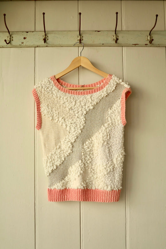 Front view of handmade cream knit vest with pink ribbed trim and textured stitches
