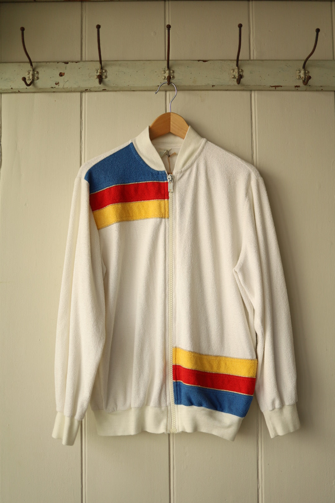 Front view of vintage cream velour tracktop with blue, red and yellow chest and hem stripes