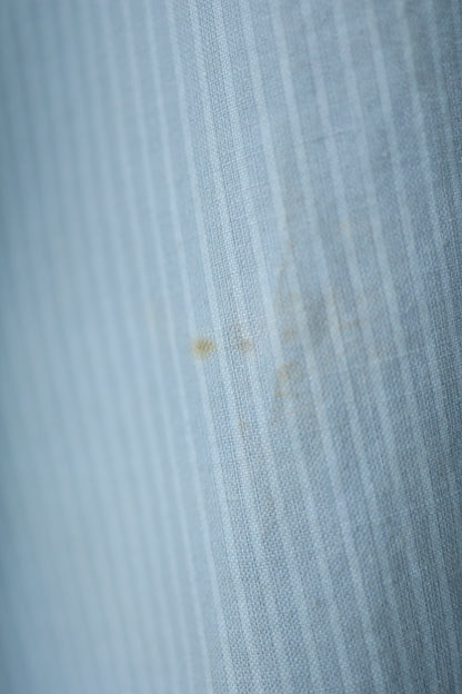 Close-up of a light stain on the front of the shirt, showing faded vertical stripes in the fabric.