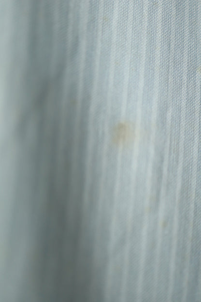 Close-up of subtle fabric wear and faint stain near the lower front section of the shirt.